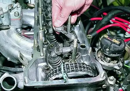 Приподнимаем рычаг клапана, освобождаем его от пружины